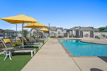 A pool with lounge chairs and umbrellas next to a pool